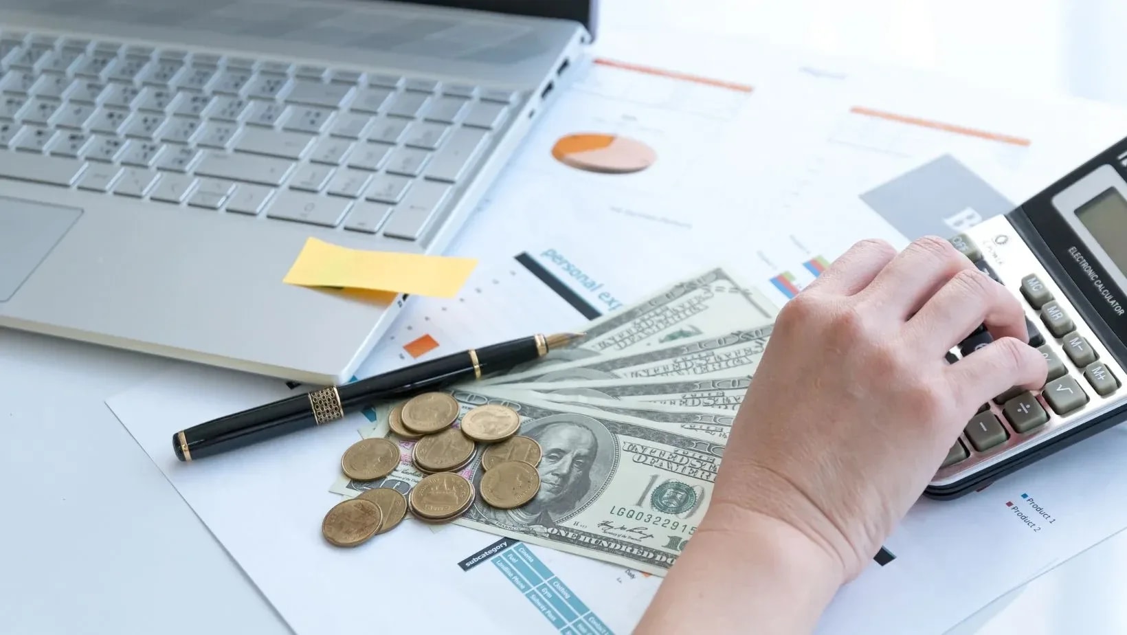 Dollar bills, coins and a calculator on a desk